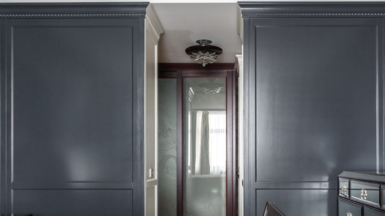 Moody room interior with dark gray wall features using a glossy finish, reflecting light from the windows
