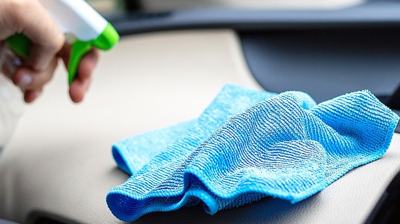 Spraying microfiber cloth with cleaner