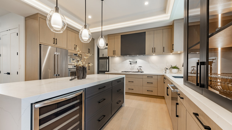 Modern kitchen with light wood cabinets, white countertops, and stainless steel appliances