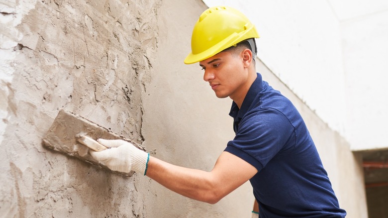 Construction worker applying cement to a  wall.