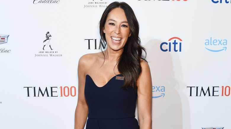 Joanna Gaines grinning in blue sleeveless dress on a red carpet