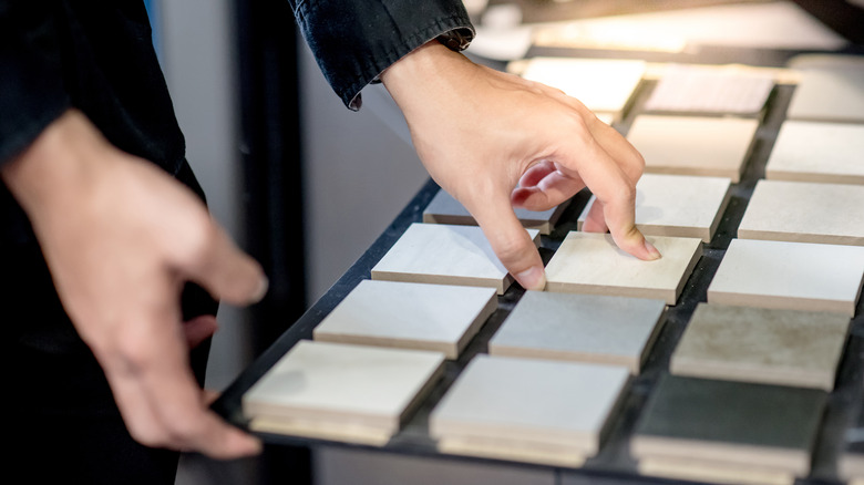 person hands examining bathroom tiles