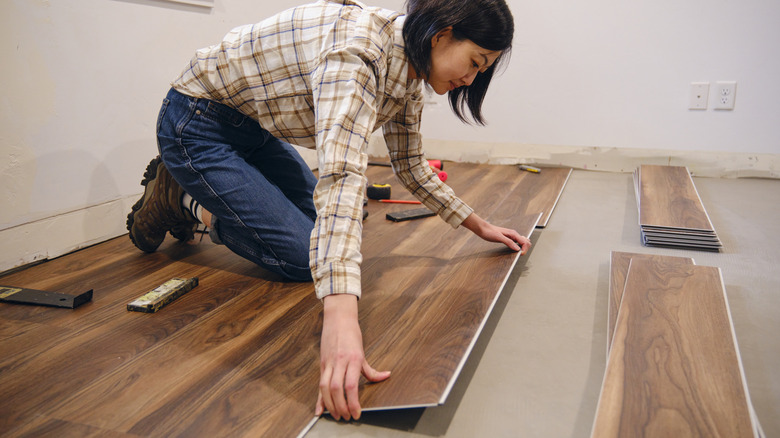 woman laying flooring in home