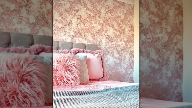 A pink bedroom with modern marble wallpaper and soft cushions and decor