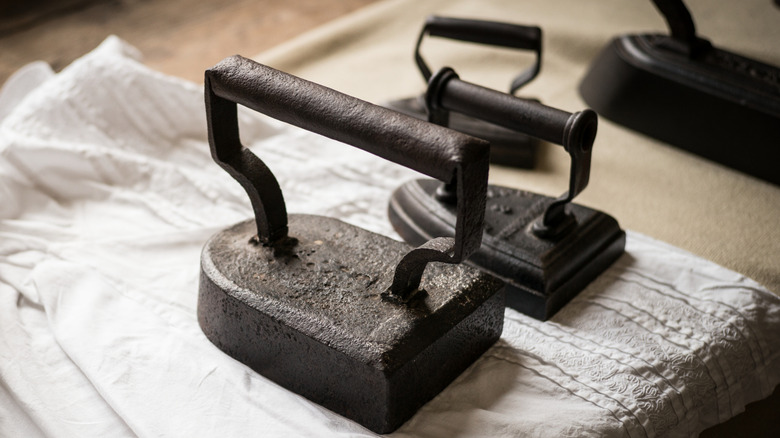 Variety of sad irons sitting on a linen item
