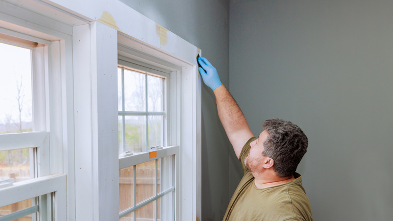 man sanding window trim