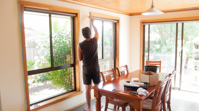 person painting wooden window trim DIY