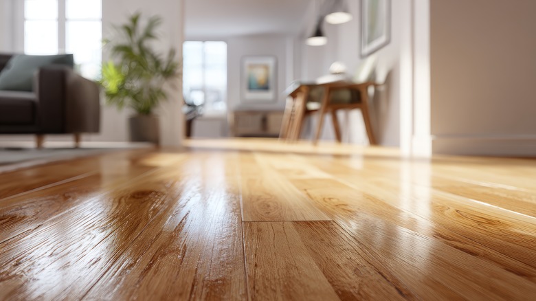 Close-up of a shiny hardwood floor with a blurred living room in the background