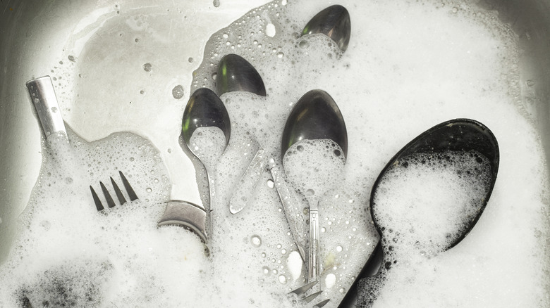 Cutlery in the kitchen sink under bubbles