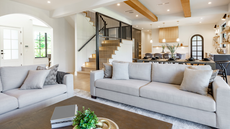 open concept neutral living room with stairs in background