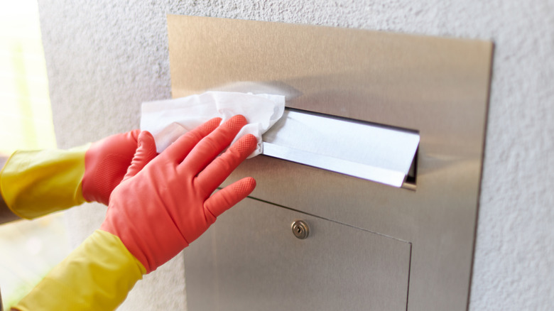 Close-up of a person with gloves cleaning a mailbox