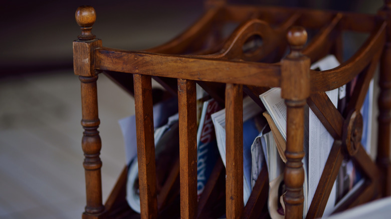 A vintage wood magazine rack holds various magazines