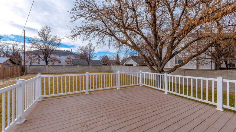 A large open back yard and deck with a direct view to neighboring houses.