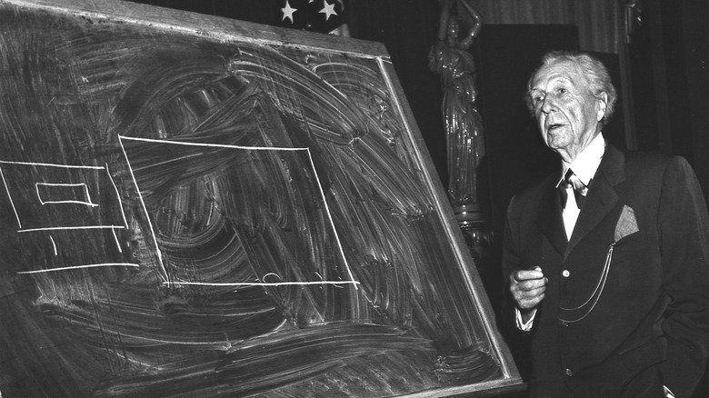 Frank Lloyd Wright with a diagram drawn on a blackboard.