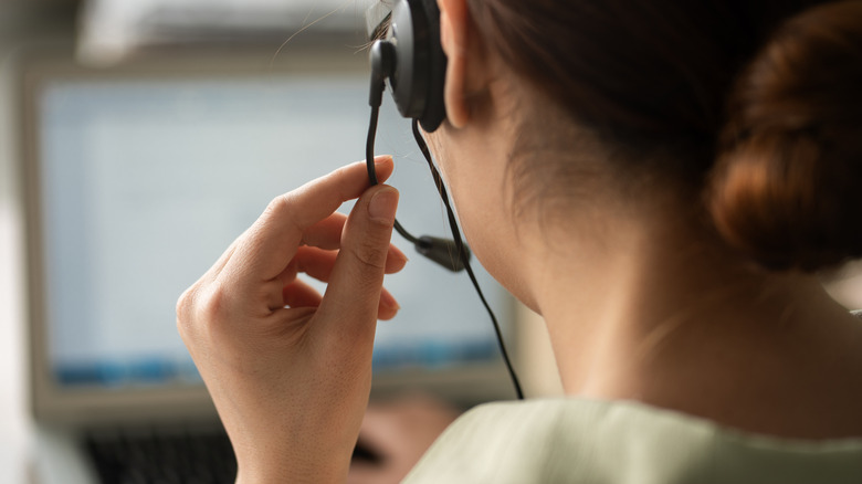 A close up of a tech support worker grabbing their headset mic