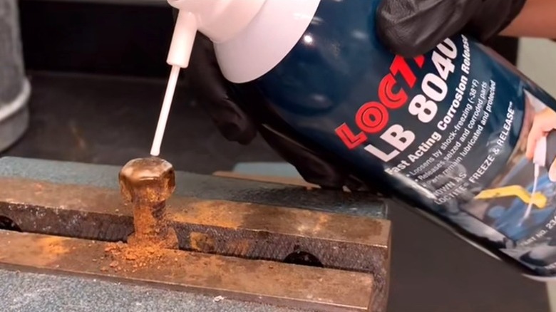 Person spraying freeze spray on rusted bolt to loosen it
