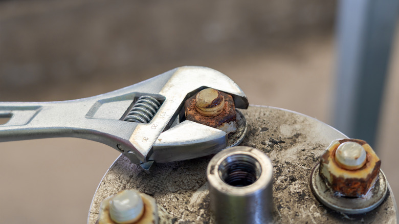 Wrench trying to loosen rust-covered bolt