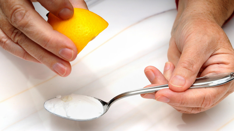 Man holding lemon and teaspoon of baking soda