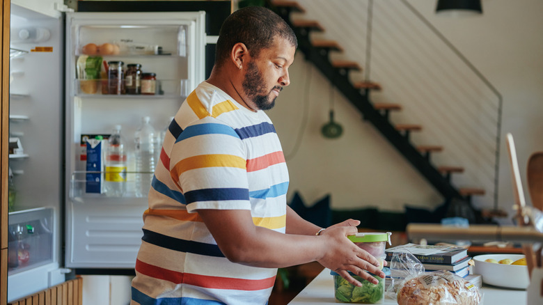 Man grabbing packed food storage containers to put in fridge.