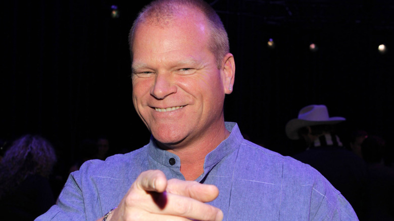 Mike Holmes smiling and pointing in a blue shirt
