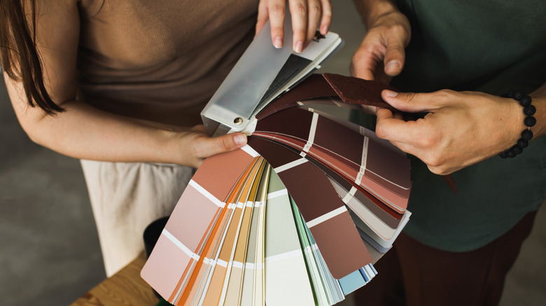 Two people sort through a catalogue of color swatches
