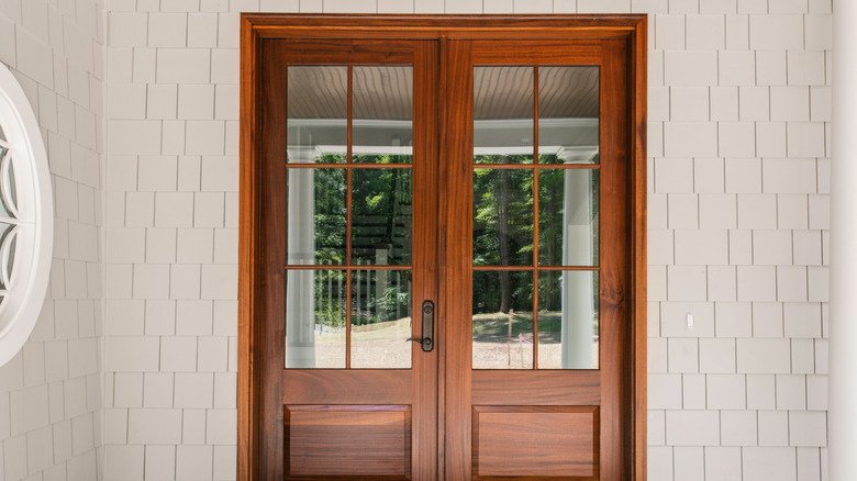 wood and glass double doors on a white home entryway