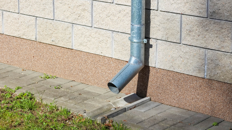 Metal downspout on the side of a tan brick building