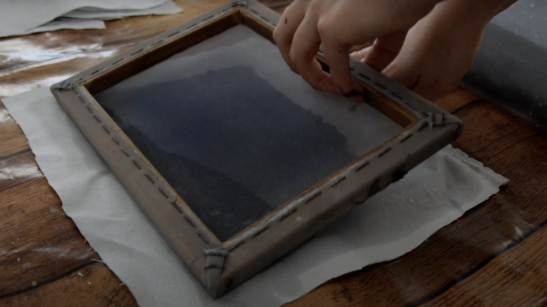 A person pressing out a piece of paper from a mould