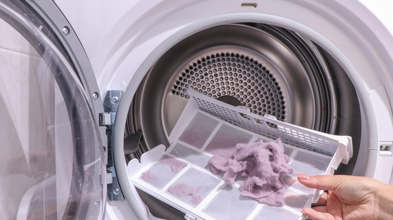 A person cleaning the lint trap in a dryer