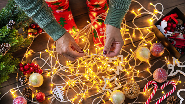 High angle view of unrecognizable woman untangling Christmas string lights for Holidays.