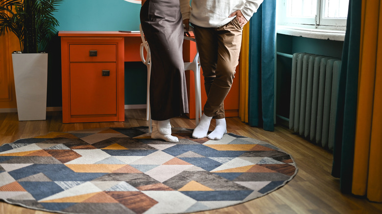 Couple standing on geometric patterned rug next to a window and desk