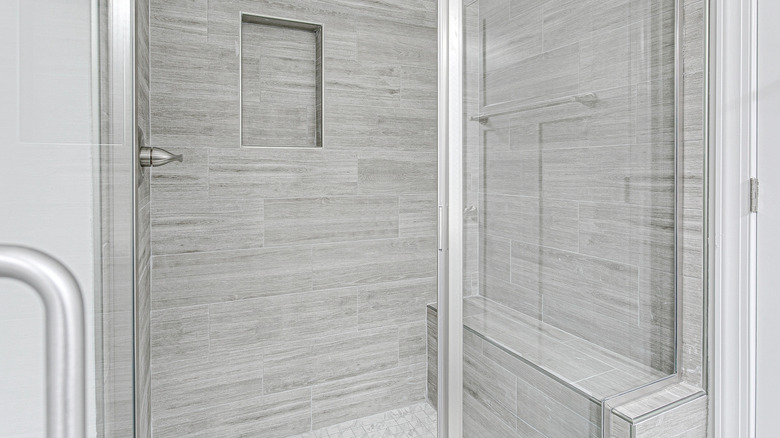 A walk in shower with a built in bench on the back wall and a niche