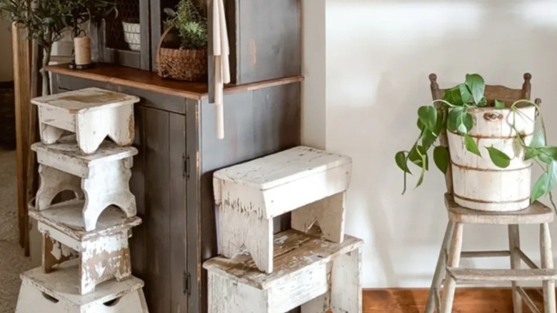 A collection of rustic whitewashed wood footstools are stacked and styled in a room.