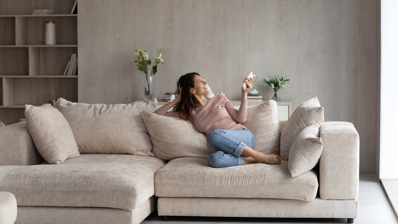 A woman sitting on a large sectional couch