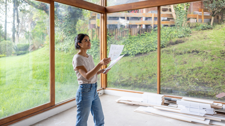 Person standing in a room reviewing remodeling plans