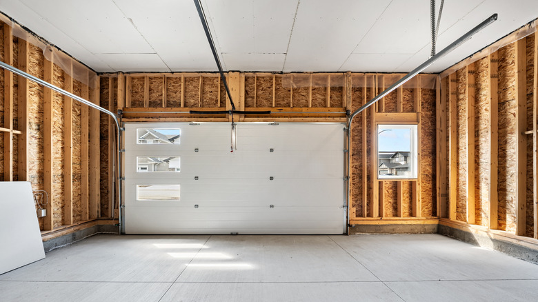 A large light-filled residential garage with exposed wall studs and a concrete floor