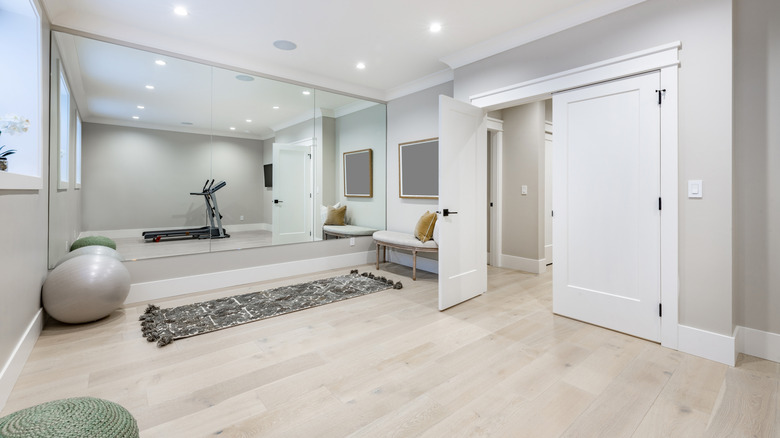 A bright home gym is shown in a converted garage with a door leading straight into the home