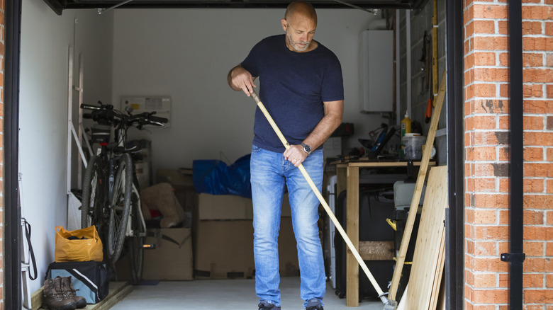 Man sweeping garage floor with broom