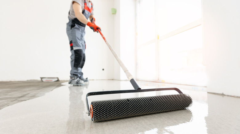 Person installing a concrete floor with a roller in a garage