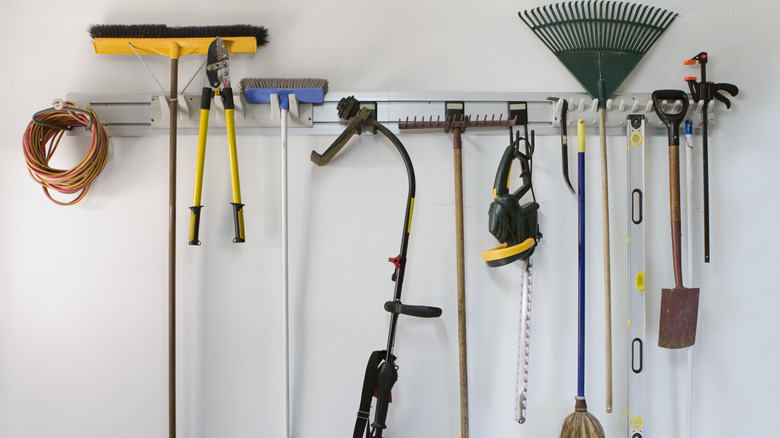 Yard tools hanging neatly on a white wall.