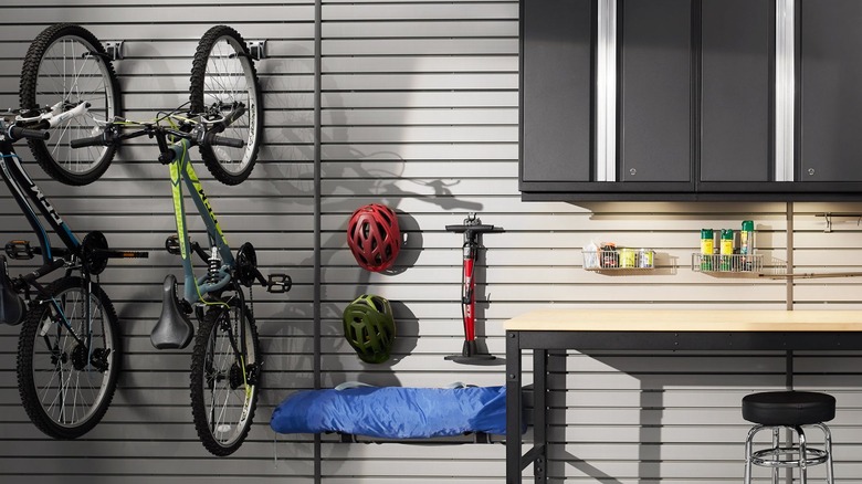 Garage slatwall with two bikes, helmets, a pump, and other stored items.