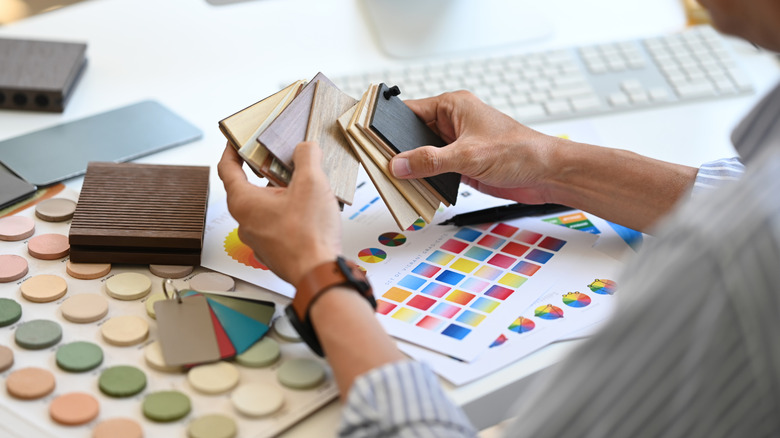 Interior designer holding color samples working on new design project at office