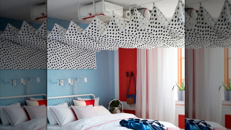 Bedroom with MULIG clothes bars suspended above bed with items stored on them