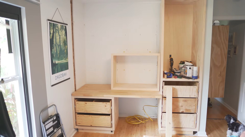 a man pieces together the parts of a built-in closet and desk combo