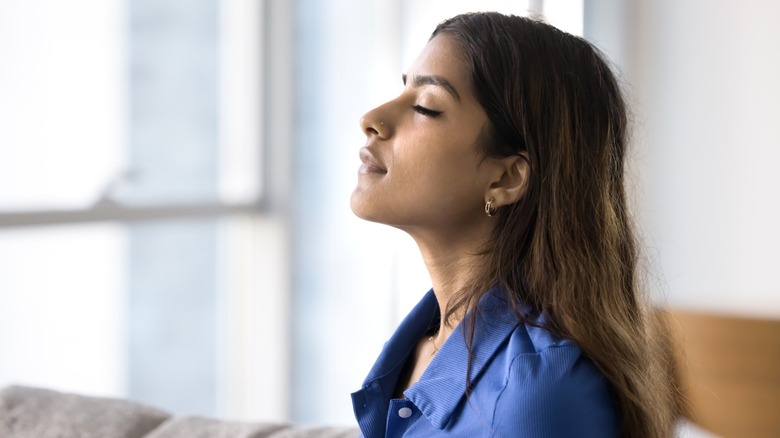 woman with eyes closed inhaling deeply in home