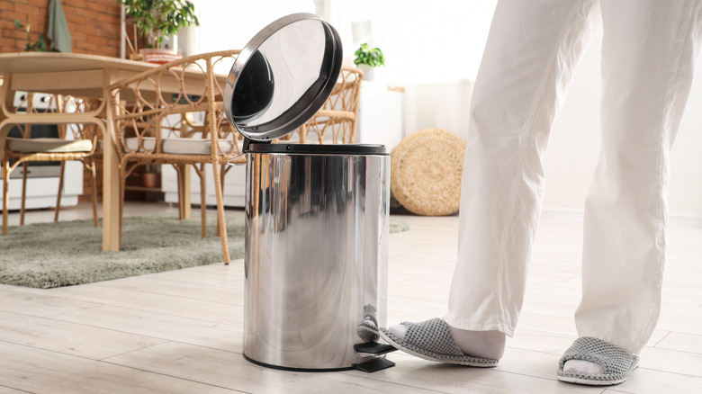 person opening a step trash can