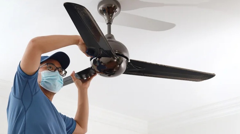 Man cleaning dusty ceiling fan