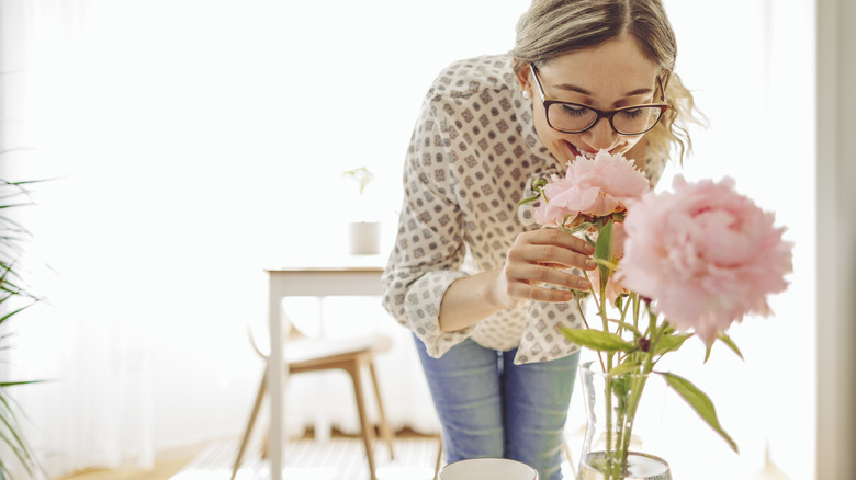 woman smelling flower in vase