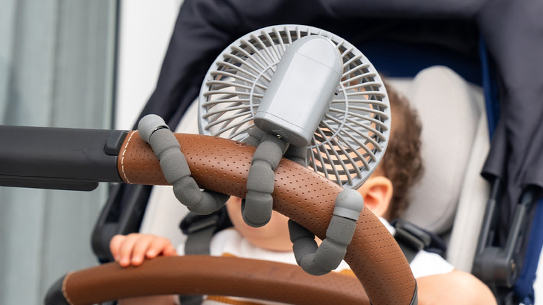 Baby in a stroller with a fan
