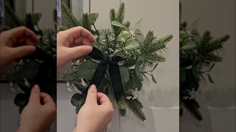 Hands arranging a bow on greenery attached to a cabinet handle